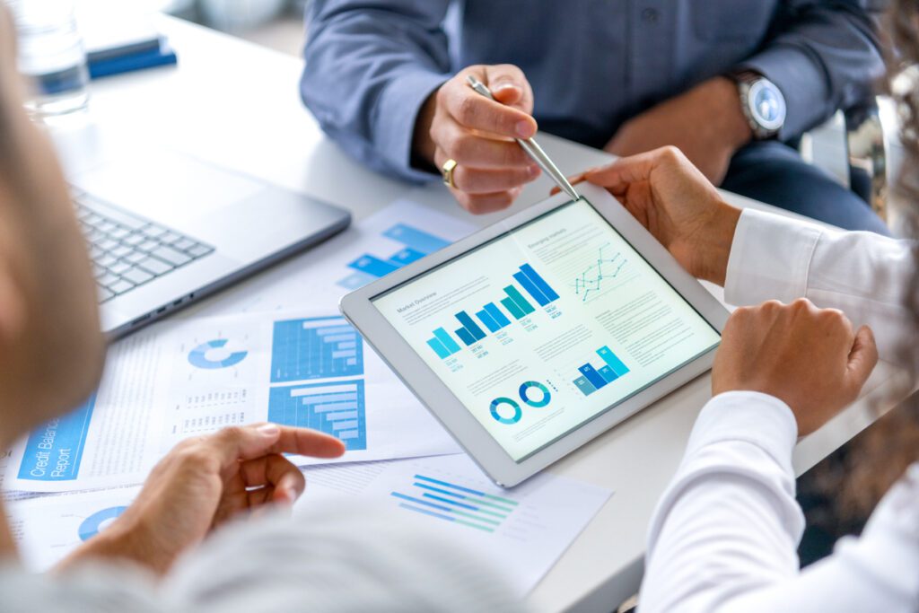 Subscription management tools: Close up of three people looking at business analytics with graphs and charts
