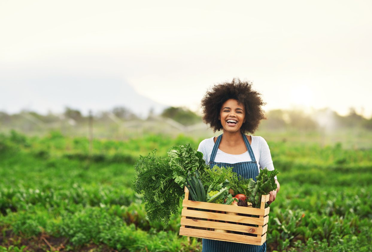 A young woman holding farm produce.