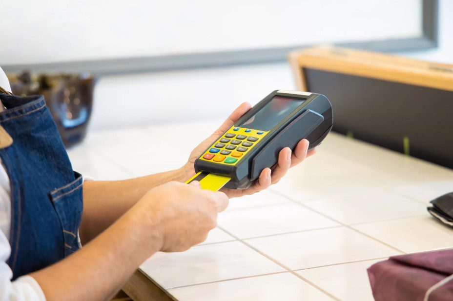 A customer taps a credit card on a handheld POS terminal for a contactless payment.