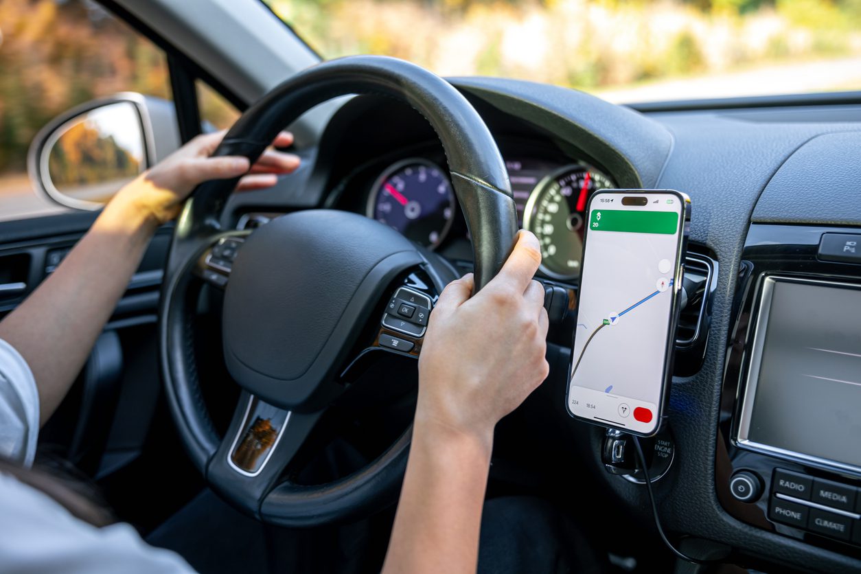 Route optimization software: A woman driving a car follows a GPS navigation map on her mobile phone