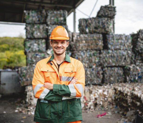 Subscription management tools: A smiling workman outdoors at a waste management facility