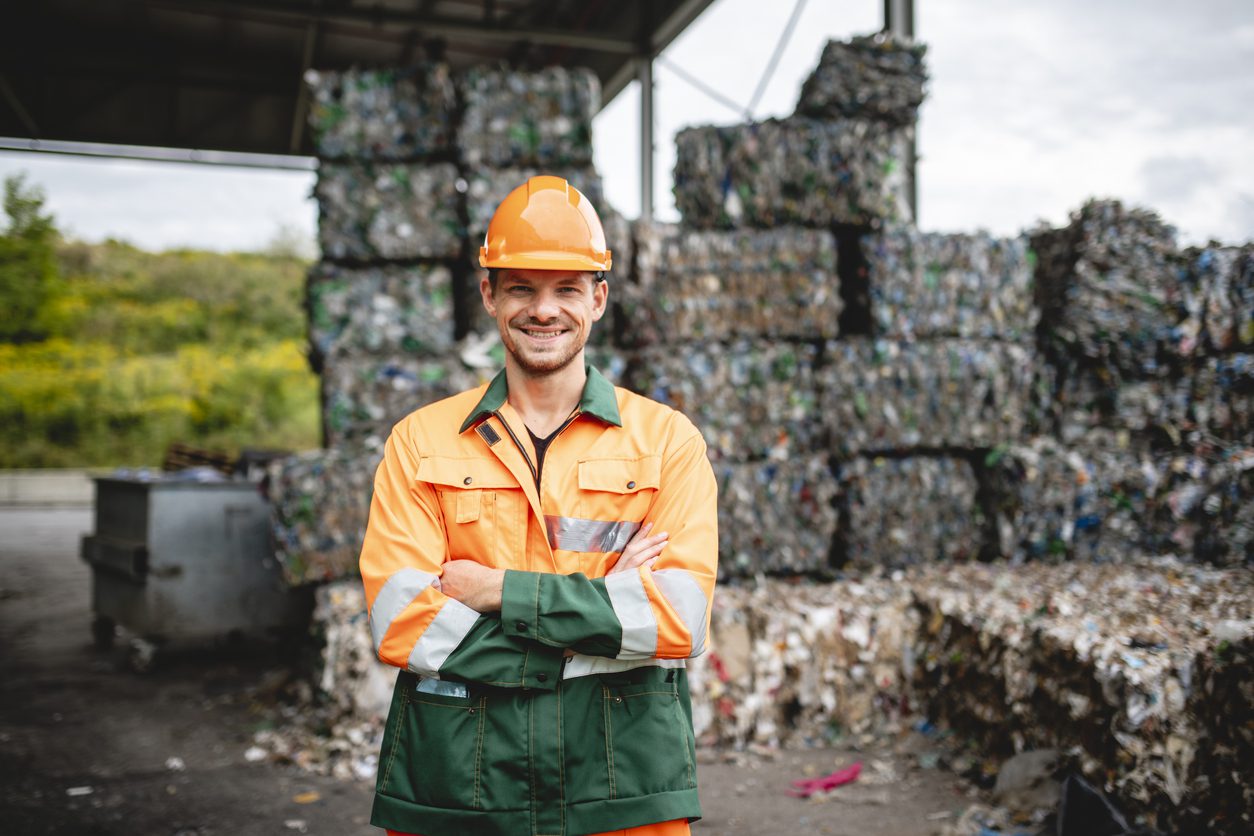 Subscription management tools: A smiling workman outdoors at a waste management facility