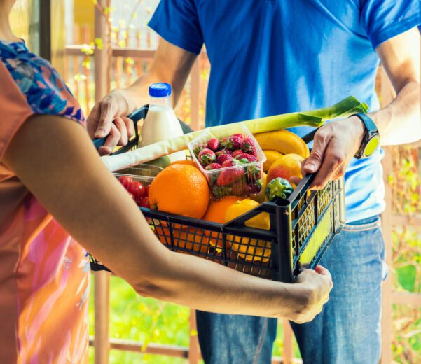 Woman accepts grocery delivery from subscription ecomerce retailer, bought with SNAP benefits.