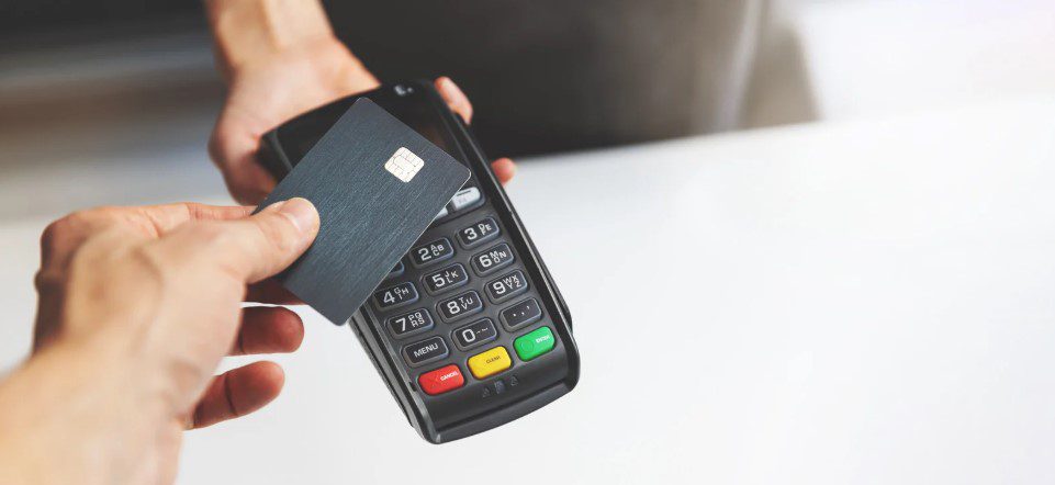 A customer taps a credit card on a handheld POS terminal for a contactless payment.